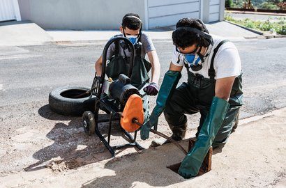 Engineers clearing a drain with a machine